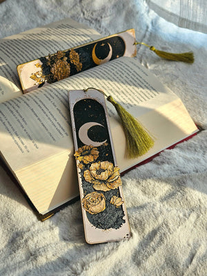 Celestial bookmarks: crescent moon and floral design with golden tones on book.
