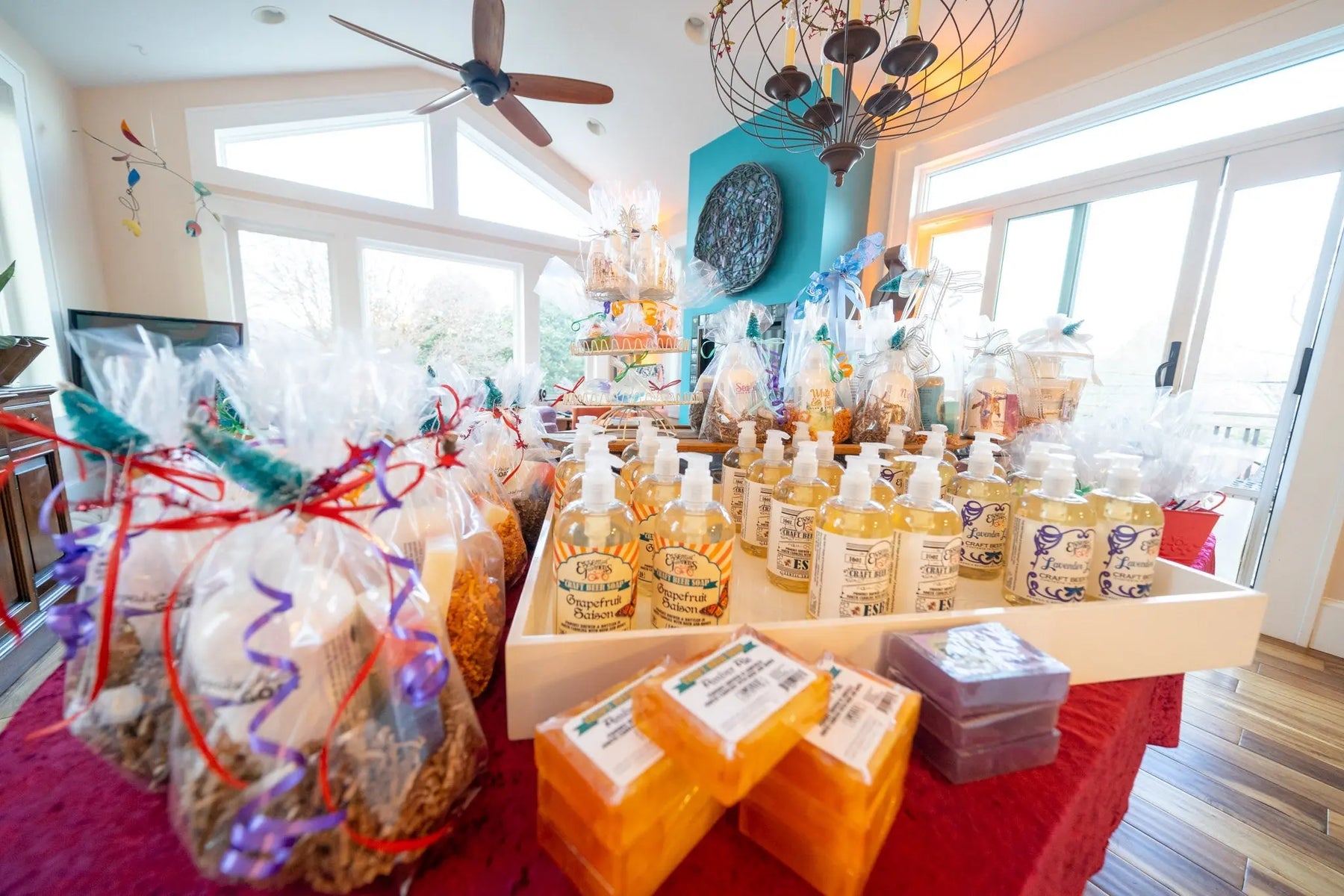 Assorted craft beer liquid soaps and bar soaps in gift sets on a red table.