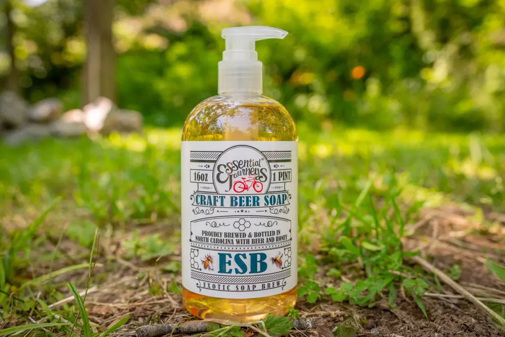 Bottle of ESB Craft Beer Soap by Essential Journeys, 16 oz, displayed outdoors on grass.