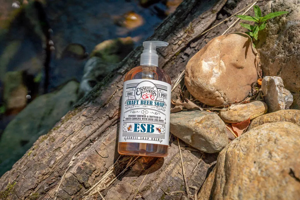 ESB Craft Beer Soap liquid in a clear pump bottle on a log and rocks.