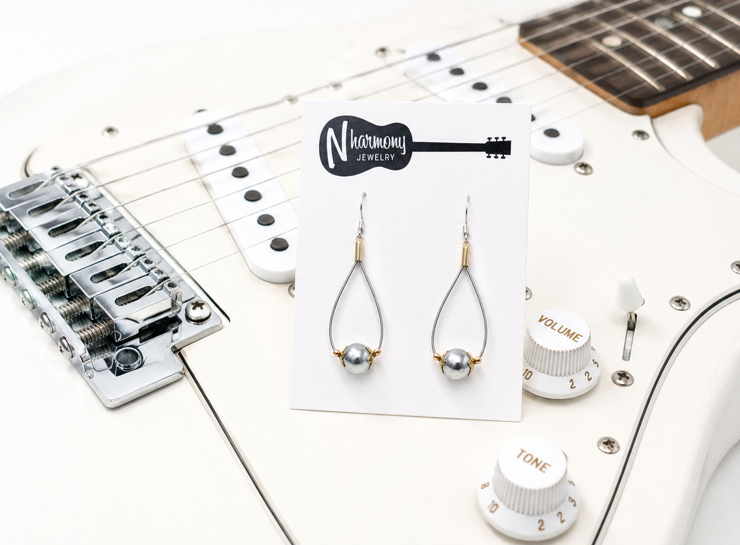 Pearl earrings on a display card with a guitar in the background