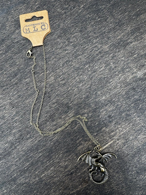 Bronze dragon necklace on gray background. Fantasy jewelry featuring a coiled wyrm pendant on a chain with a tag.