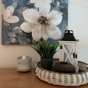 Eucalyptus spearmint wax melt in a ceramic dish with a green plant and lantern on a woven tray.