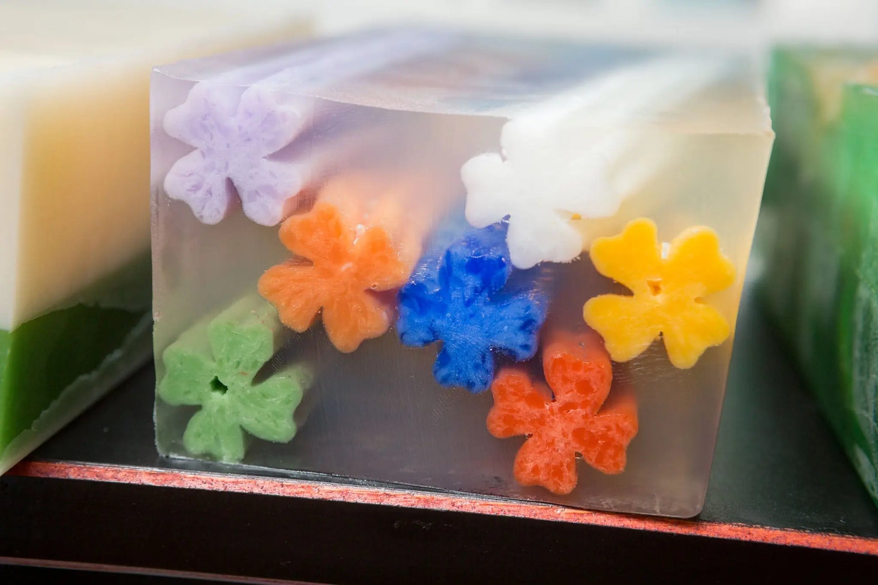 Clear soap slice with colorful flower shapes embedded inside.