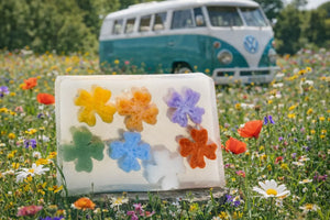 Clear soap slice with colorful flower shapes and wildflower meadow background.