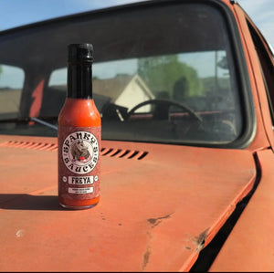 Spanky's Sauces Freya hot sauce bottle on the hood of an orange truck.