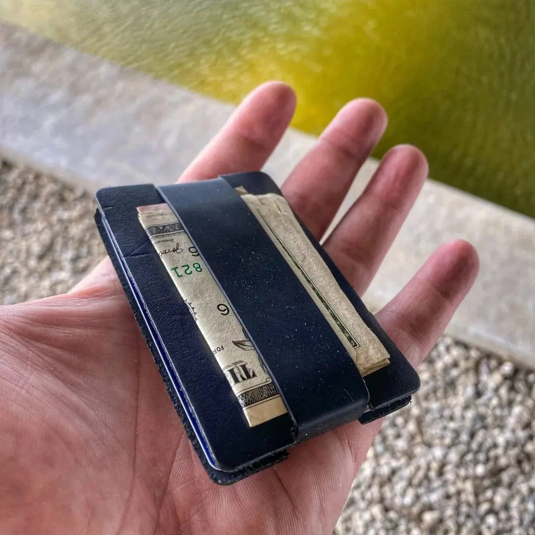 Black leather card wallet with elastic band holding folded bills