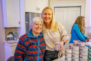 Two women holding a jar of Ginger Quince Goats Milk Body Butter.