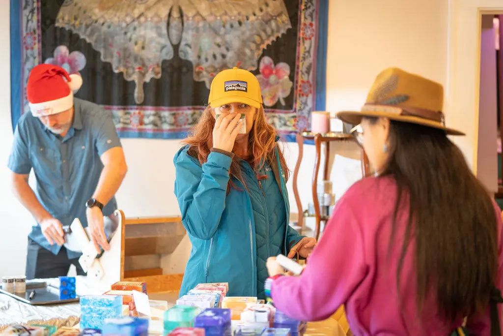 People at a table with colorful soaps, one wearing a Santa hat.