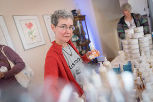 Woman holding grapefruit goats milk lotion bottle and bar of soap at Main Street Collective.