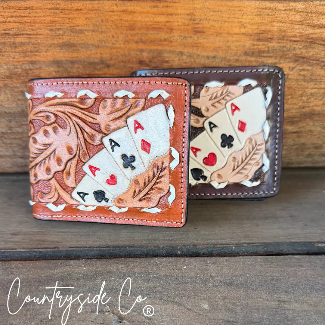 Two leather men's wallets with hand-tooled designs and painted card suits.