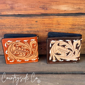 Two tooled leather men's wallets, one orange and one brown, with white stitching.