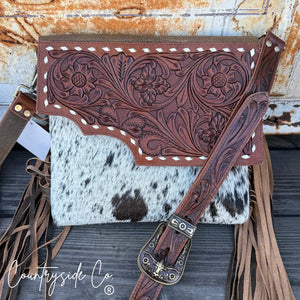 Brown tooled leather purse with white stitching and cowhide accent.