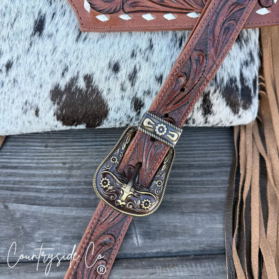 Countryside Co. tooled leather purse strap with ornate buckle and cowhide accent.