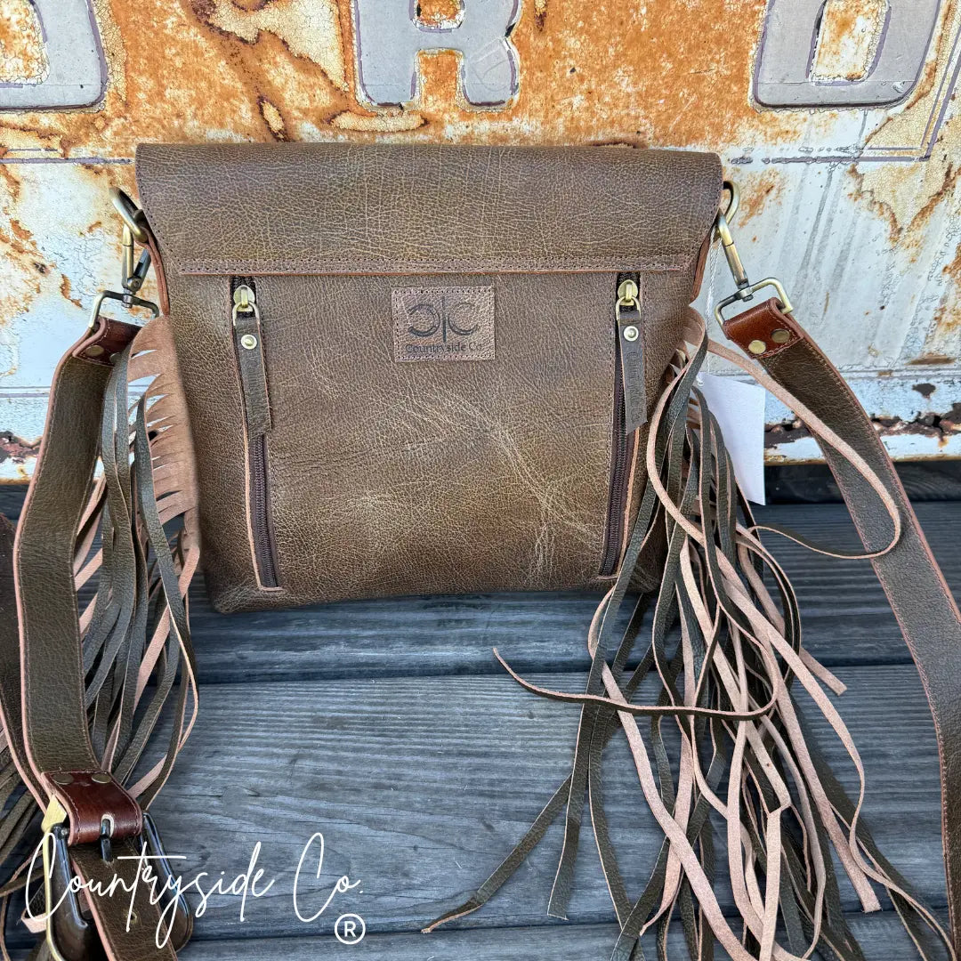 Brown tooled leather conceal carry purse with fringe and front zipper pockets.