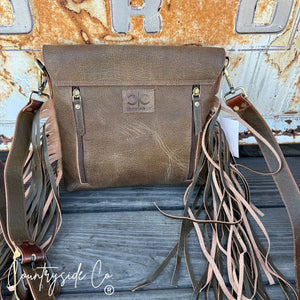 Brown tooled leather conceal carry purse with fringe and front zipper pockets.