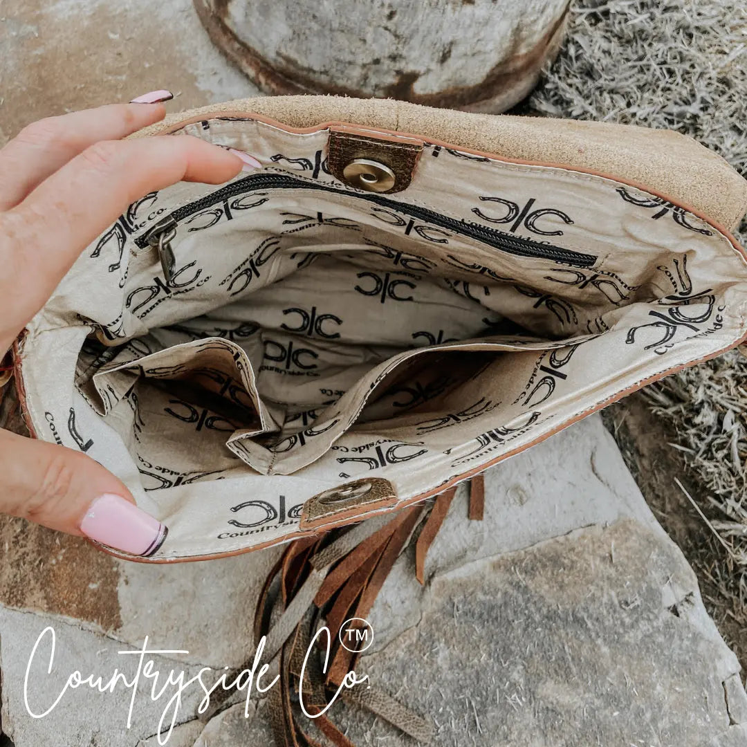 Interior of tan leather purse with multi-pocket lining and branded horse logo pattern.