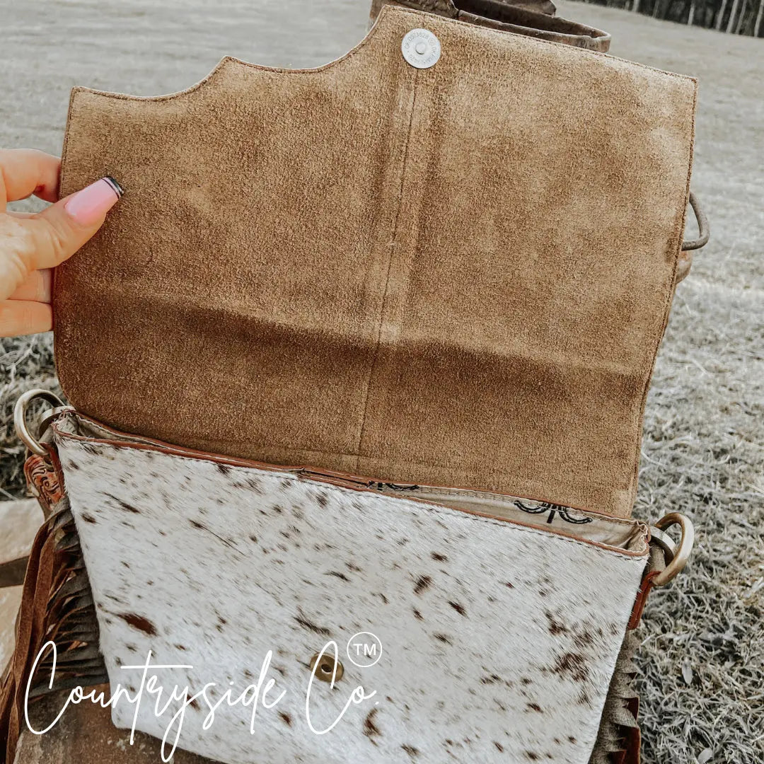 Conceal carry purse with cowhide and tooled leather flap open.