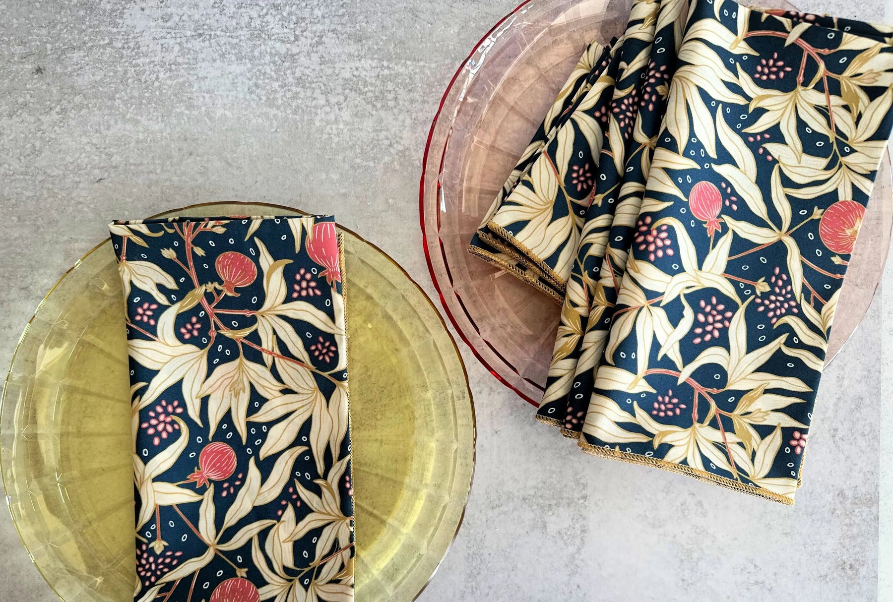 Navy blue floral pattern cloth napkins on yellow and pink glass plates.