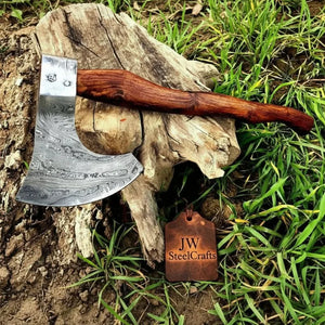 Damascus steel axe head with wood handle on rustic wood surface