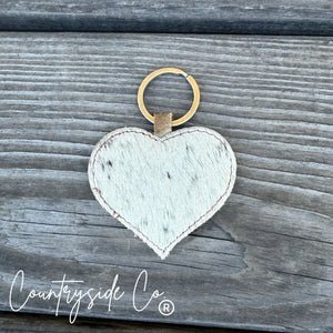 Heart shaped cowhide keychain with gold ring on wood