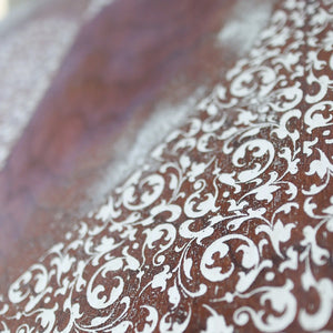 Wooden surface with white filigree pattern and blurred background.