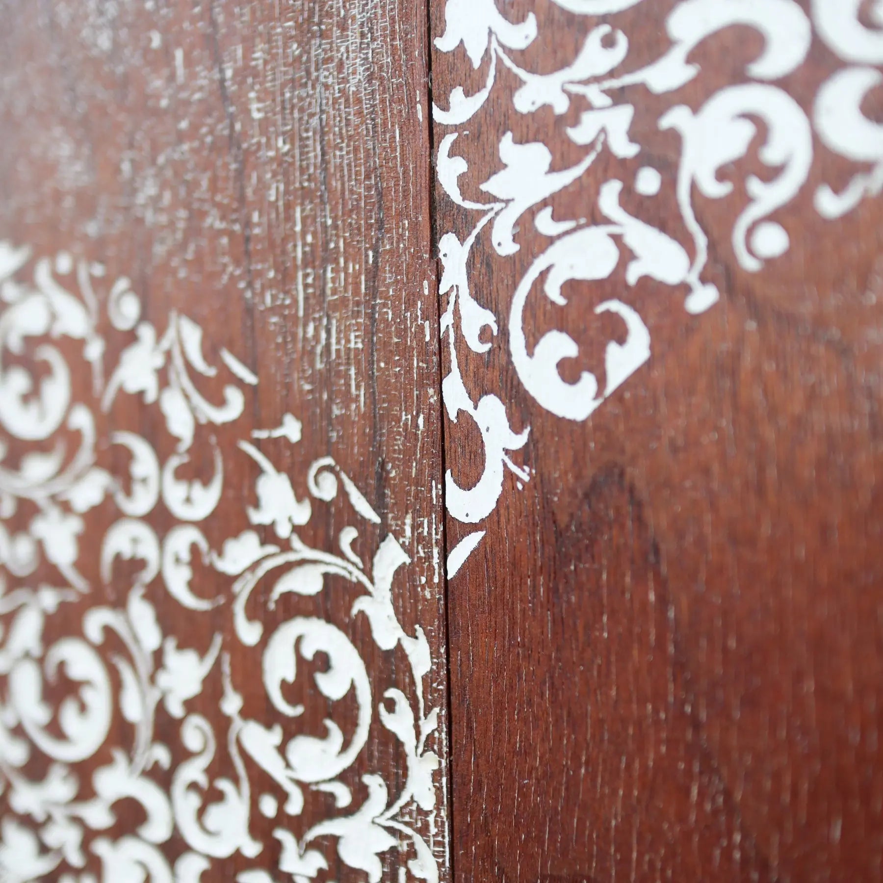 Close-up of a white filigree pattern on a dark wood surface.