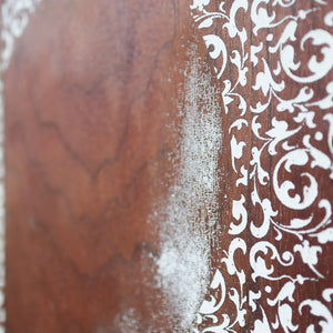 Close-up of white filigree pattern on distressed wood print.