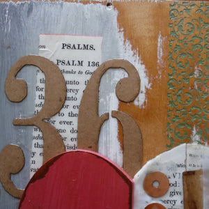 Collage art with Psalm 136 Bible pages, cardboard letters, and a red shape on wood.