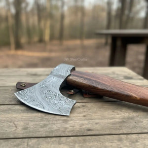 Damascus steel axe head with wood handle on rustic wood surface