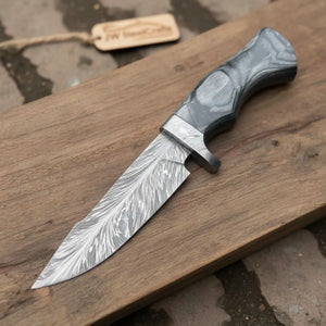 Handmade damascus steel knife with wood handle on dark surface