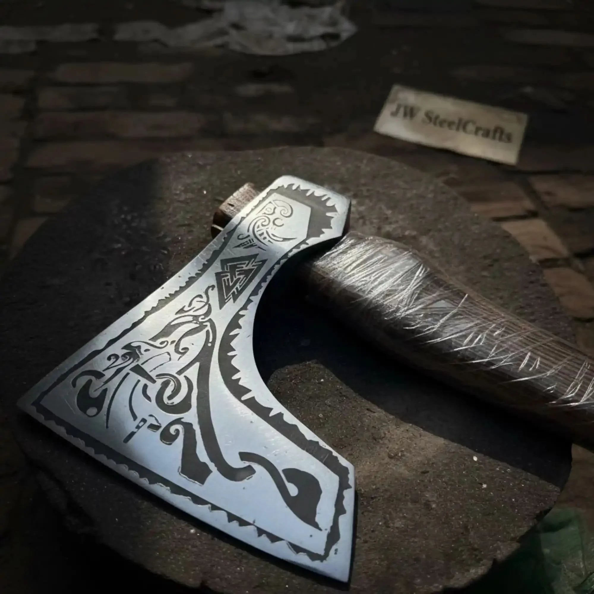 Damascus steel axe head with wood handle on rustic wood surface
