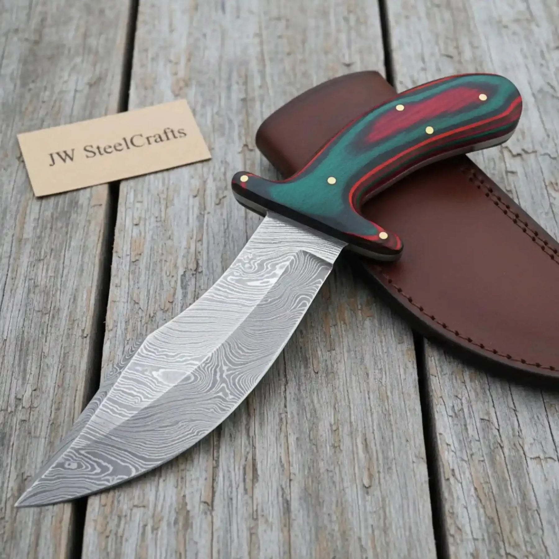 Handmade damascus steel knife with wood handle on dark surface