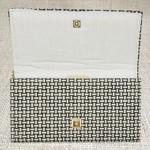 Jana Crossbody Clutch with woven black and white grasscloth and gold snap closure.