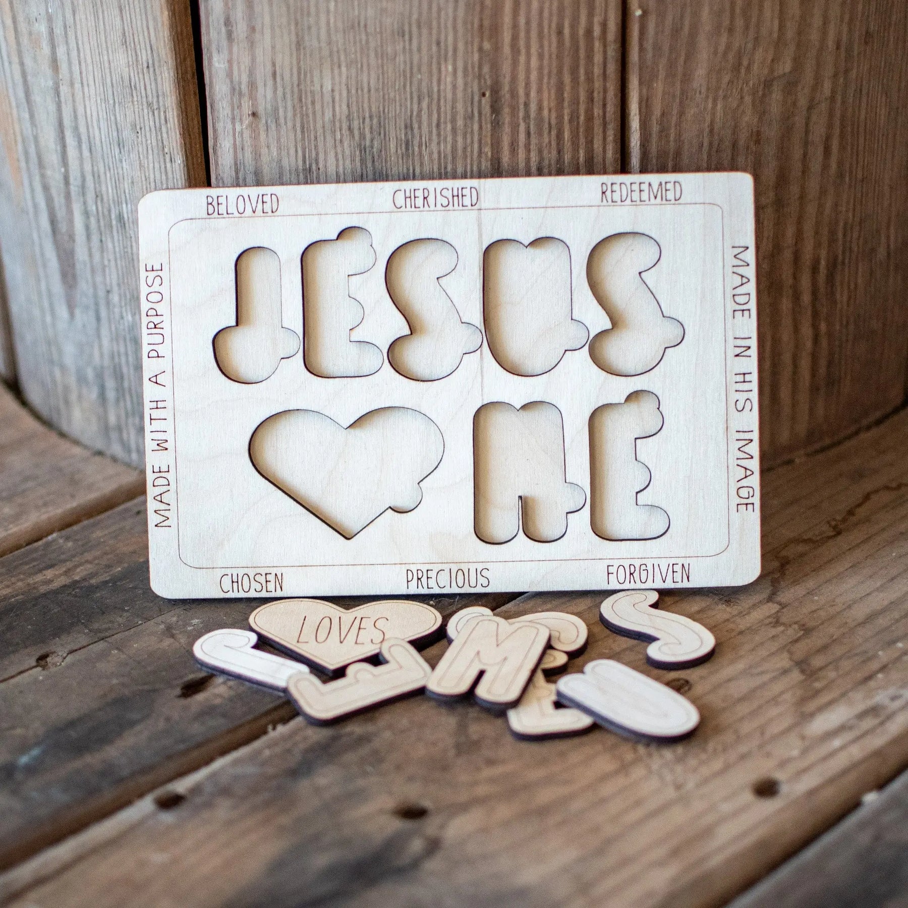 Wooden 'Jesus Loves Me' puzzle with letter cutouts and descriptive words.