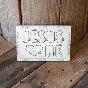Wooden "Jesus Loves Me" puzzle with text and heart shape.