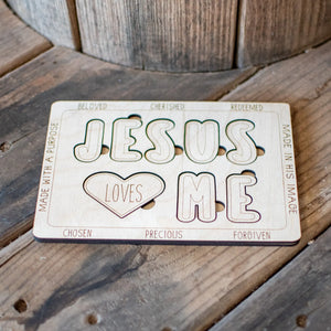 Wooden 'Jesus Loves Me' cutout puzzle with encouraging words on a wood surface.
