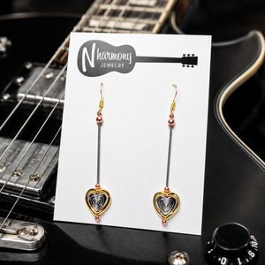 Heart-shaped earrings on a 'N Harmony Jewelry' card with a guitar in the background