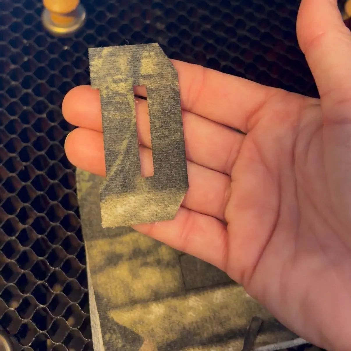 Hand holding a cut fabric letter 'D' with a cutout.