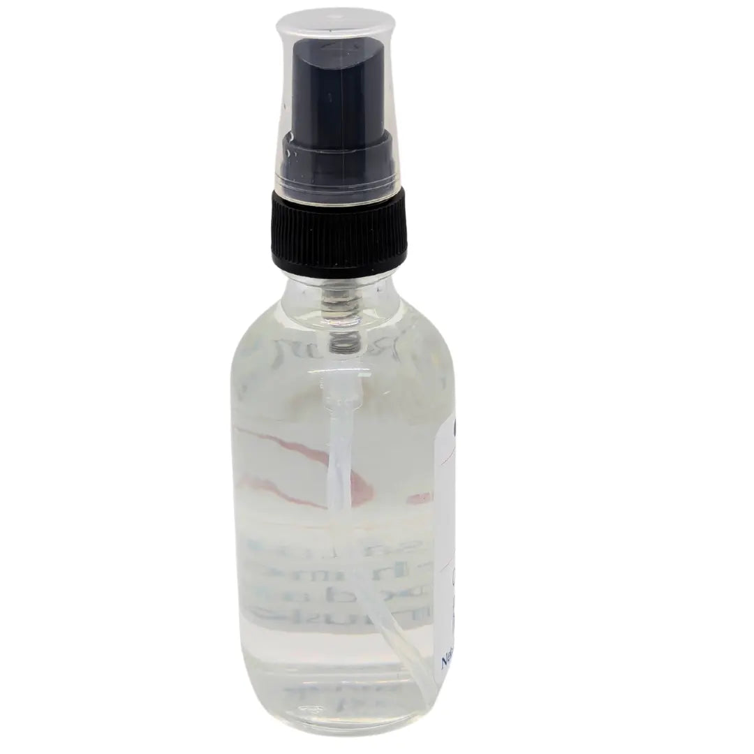 Clear glass spray bottle with black nozzle containing a translucent liquid.