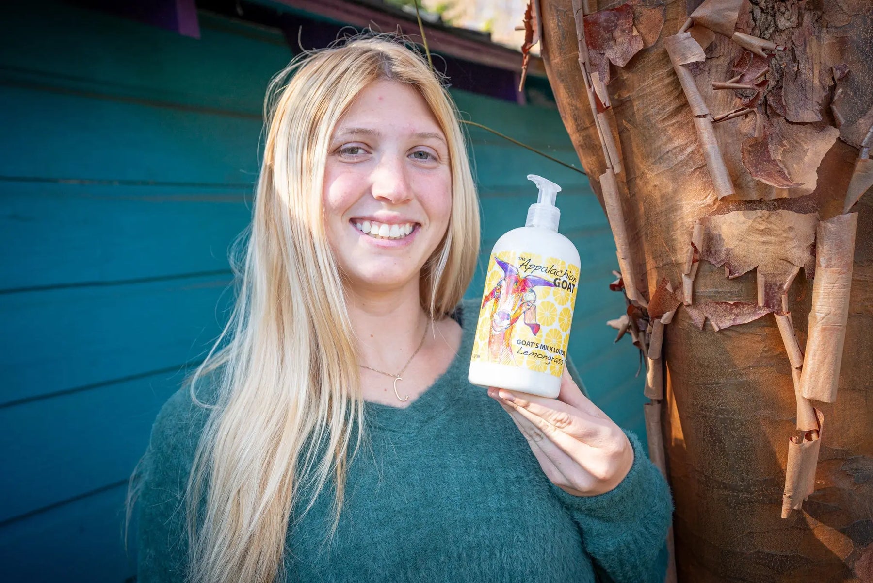 Woman holding a 16 oz bottle of Appalachian Goat's Milk Lotion in Lemongrass scent.