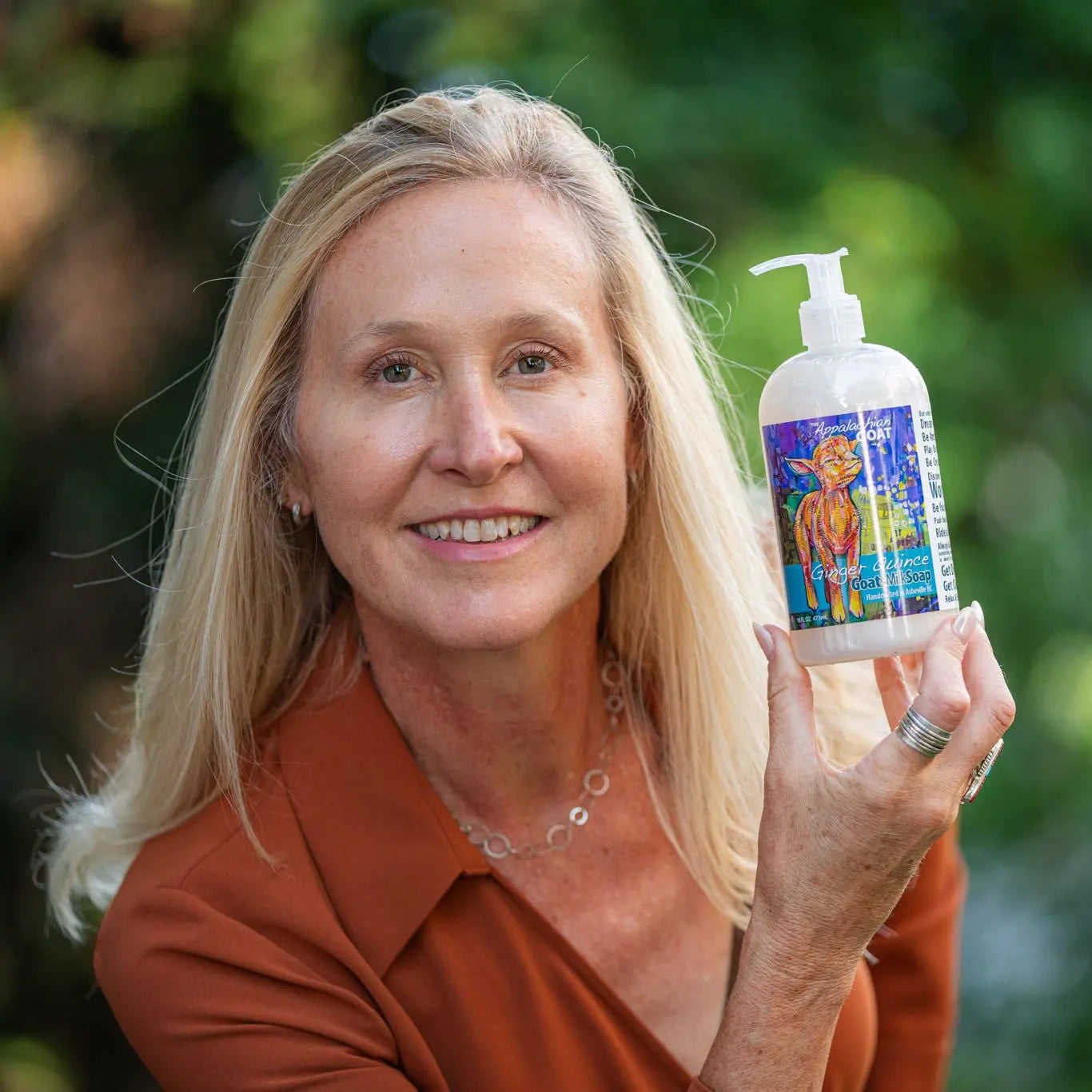 Woman holding a bottle of Ginger Quince Goat Milk Liquid Soap.