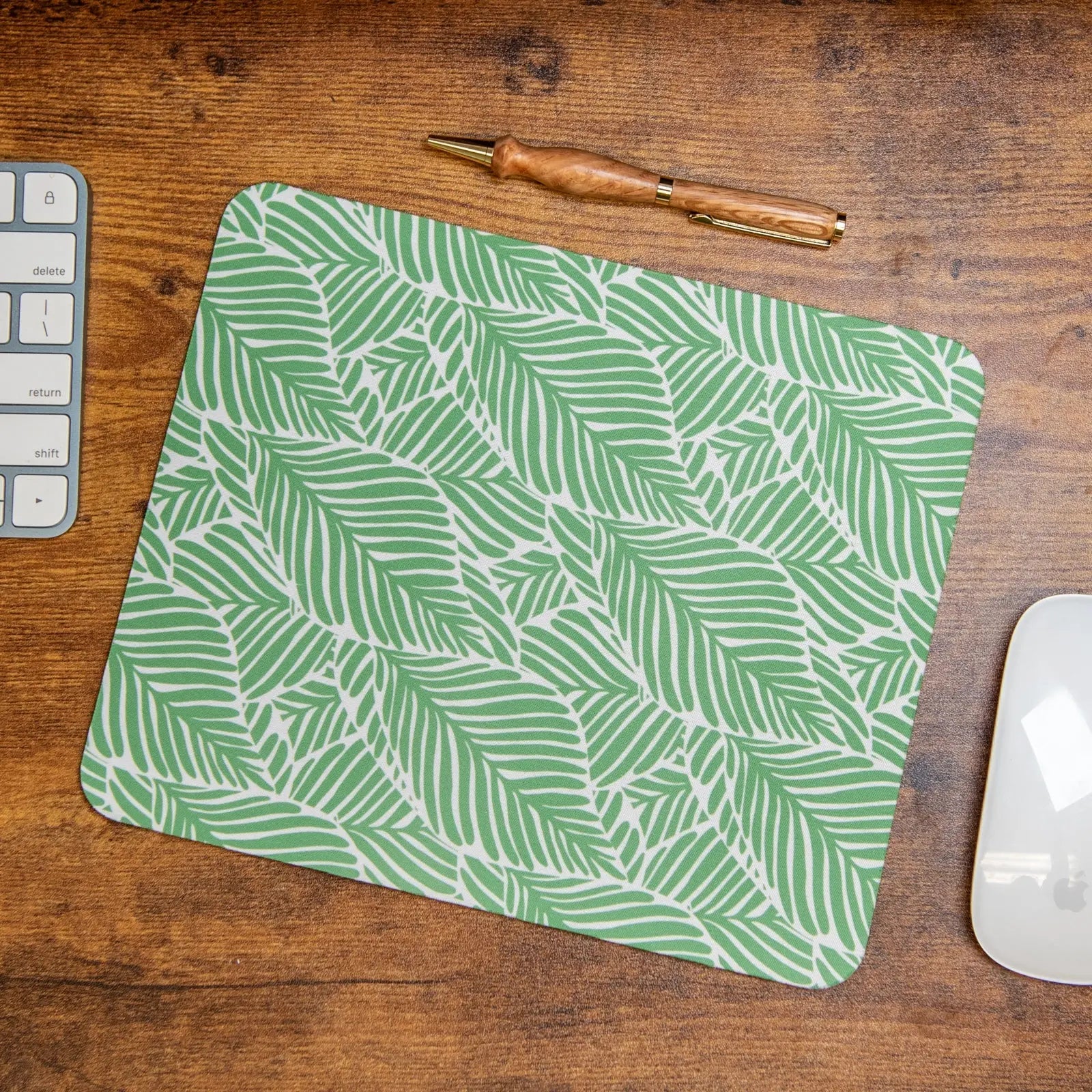 Green leafy pattern mouse pad on a wooden desk.