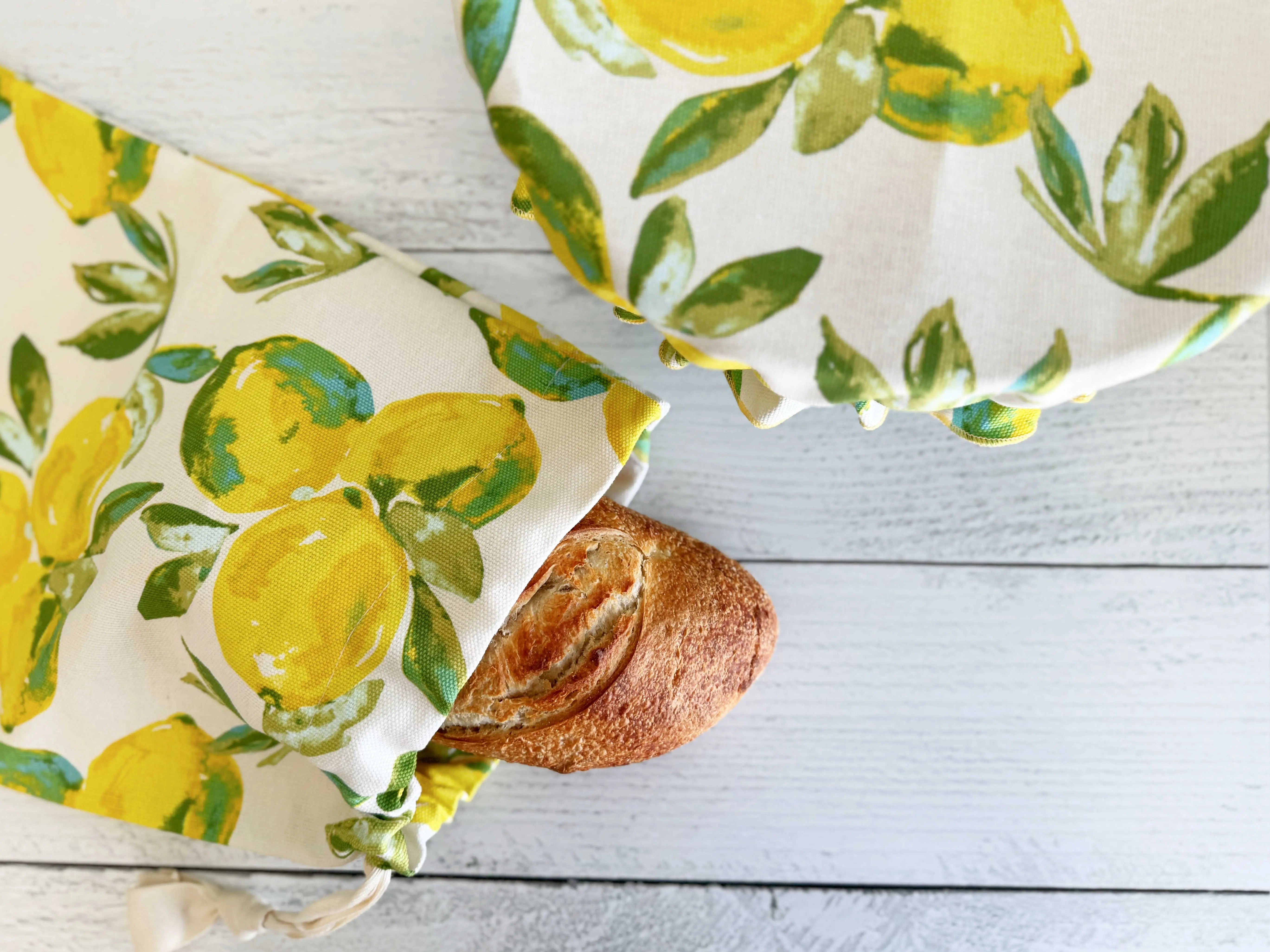 Bread bag with lemon print and a loaf of bread next to a bread cover.