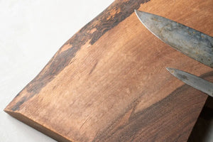 Wooden knife holder with two metal knives resting on a reclaimed wood surface. Magnetic knife strip.