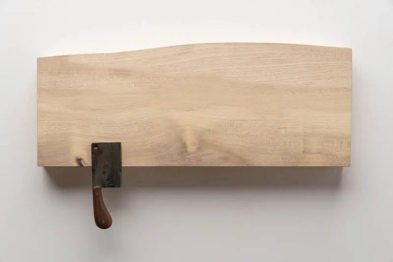 Wooden magnetic knife holder with cleaver against a white wall. Kitchen storage and organization.
