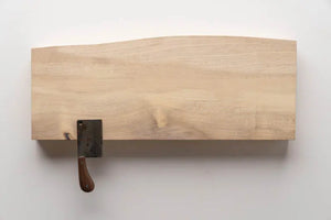 Wooden magnetic knife holder with cleaver against a white wall. Kitchen storage and organization.