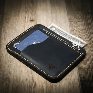Black leather minimalist wallet holding cards and cash with visible stitching.