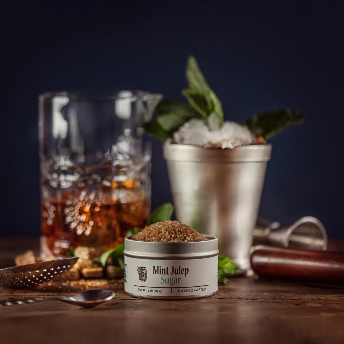 Mint Julep Sugar tin with bourbon, mint, ice, and bar tools on a wooden surface