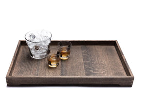 Wooden tray holding two glasses with liquor and ice bucket with ice cubes.